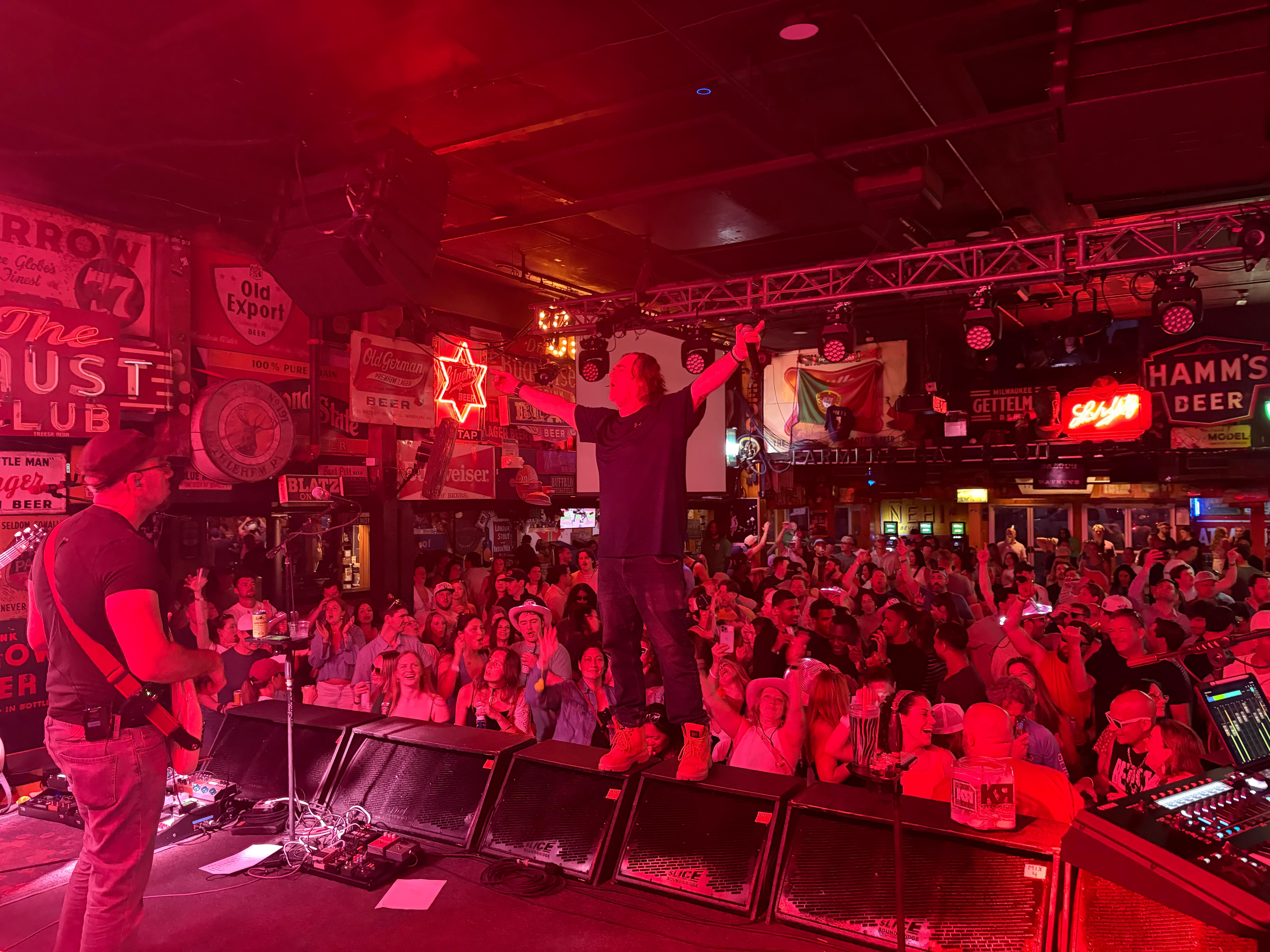 KleptoRadio performing for a packed crowd under red stage lights